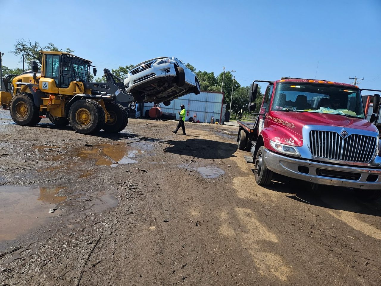 Loader lifting a vehicle onto a truck at our Kentucky salvage yard